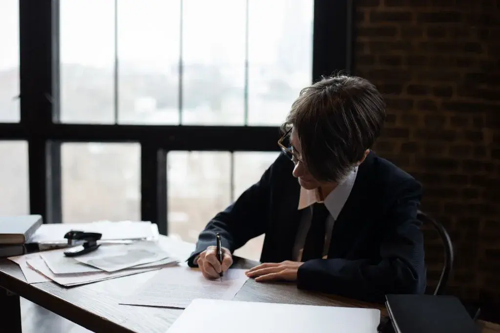 Legal professional reviewing and signing documents at a desk